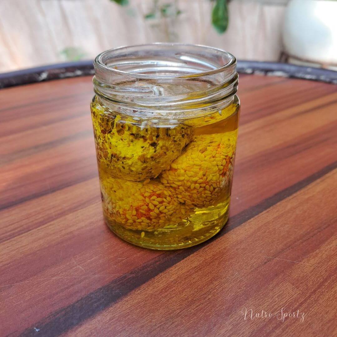 An image of labneh balls immersed in olive oil in a jar.