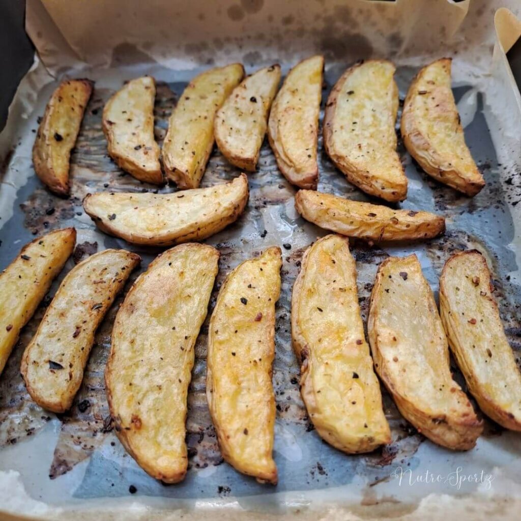 An image of baked potato wedges in a baking tray.